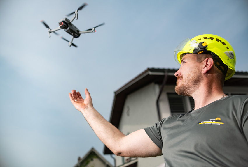Mann mit Drohne bei Dachkontrolle