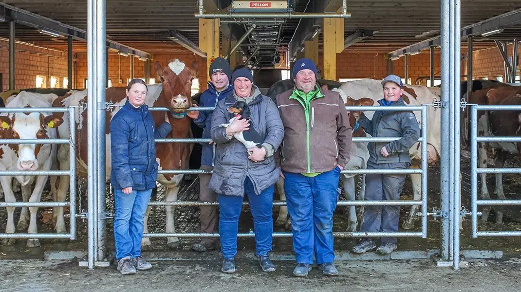 Die ganze Familie vor dem Stall, im Hintergrund sind Kühe