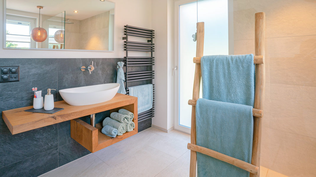 Trend-Badezimmer mit moderner Einrichtung, Holzelementen, blauen Tüchern und schwarzem Radiator 
